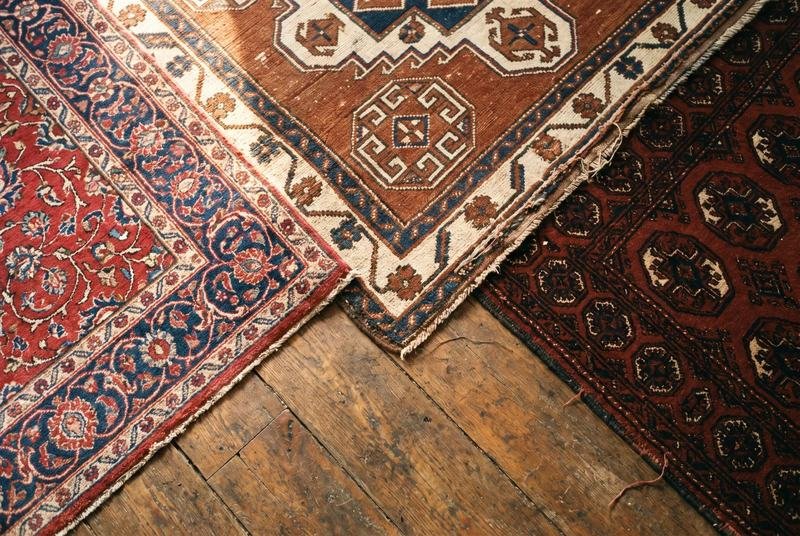 Trois angles de tapis persan, caucasien et turkmène posés côte à côte